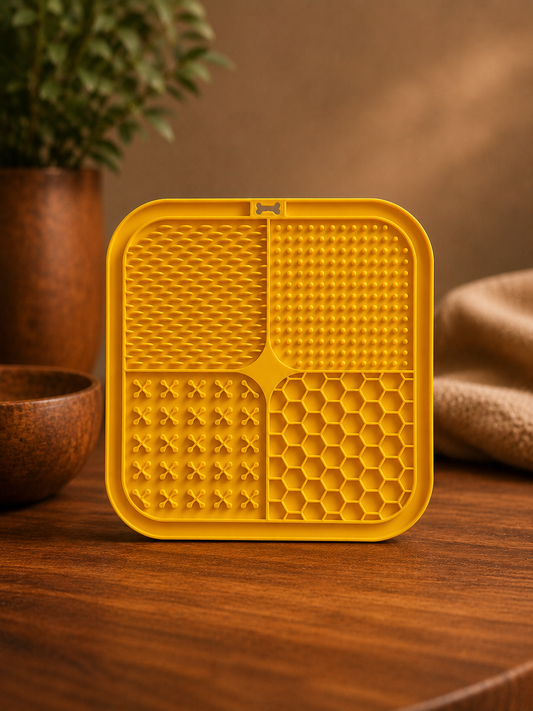 Yellow textured square object on a wooden surface with a plant in the background