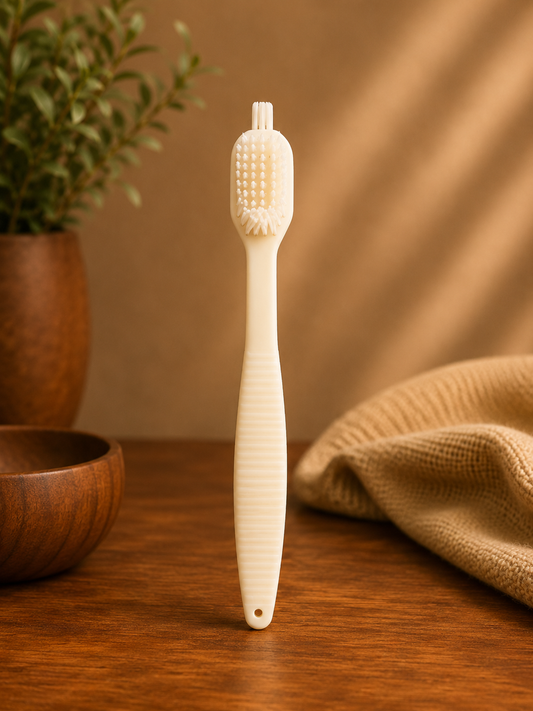 White bristle brush on a wooden surface with a plant and towel in the background