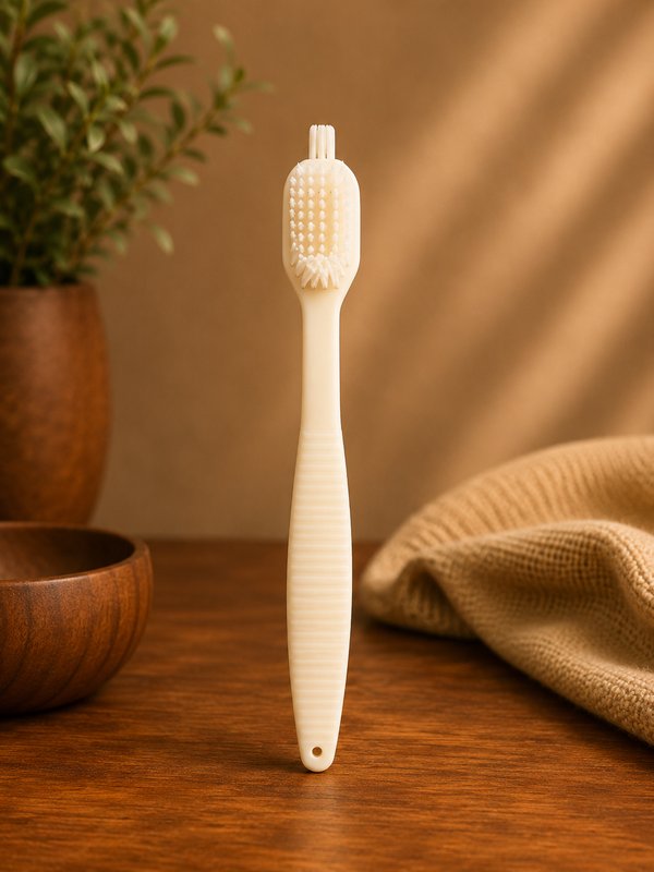 White bristle brush on a wooden surface with a plant and towel in the background